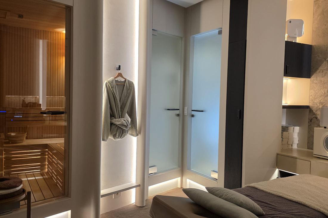 Nucellin changing area with hanging robes, frosted glass doors and a dry sauna behind glass.