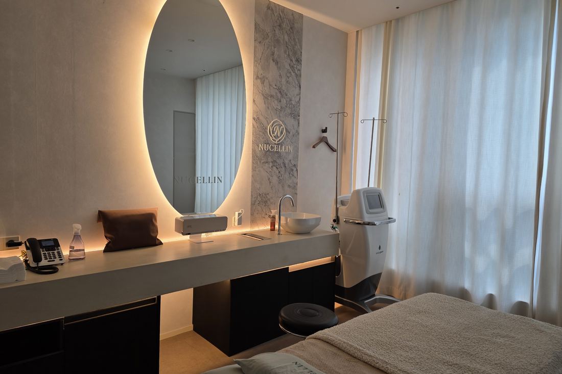 A private treatment suite at Nucellin with a lit oval mirror, a stone vanity and a treatment bed.